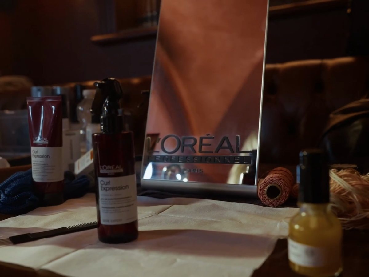 A L'Oréal Professionnel mirror, Curl Expression bottles, a comb and a spool of twine on a styling table backstage at Irish Fashion Week