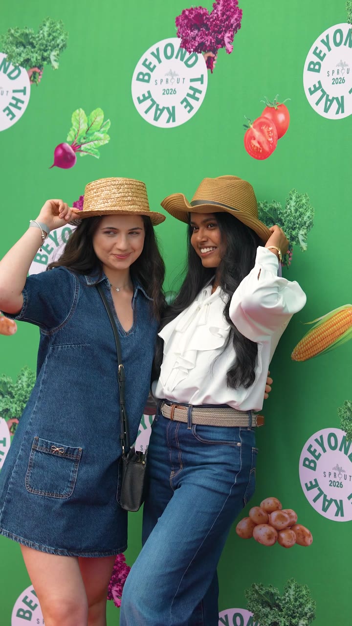 Two guests in straw hats pose at the Beyond the Kale photo backdrop at the Sprout & Co summer BBQ