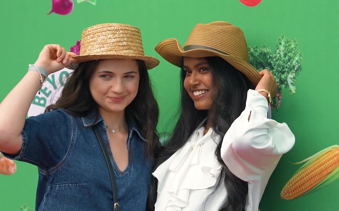 Sprout & Co summer BBQ film still: two guests in straw hats at the Beyond the Kale photo backdrop